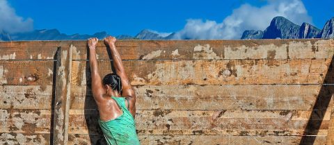 Strong and toned trainer climbing over a wall