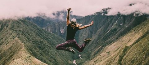 woman jumping on top of a mountain